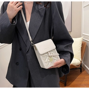Detail shot of white woven crossbody bag with metal pendant and logo on grey blazer