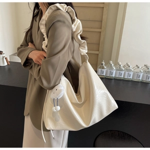 Close-up of cream PU leather tote bag with floral embossing and ruffled shoulder strap