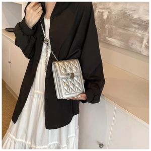 Close-up of silver quilted crossbody bag featuring a heart-shaped metal lock and chain