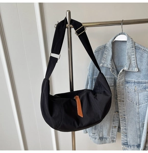 Detailed view of black nylon crescent bag on hanger featuring durable fabric and wide strap