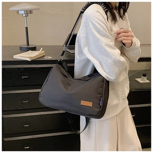 Détail du sac cabas noir en toile avec bandoulière tissée et écusson en cuir