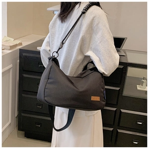 Détail d'un sac en toile noir avec bandoulière en corde tressée et étiquette cuir