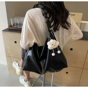 Detail of black large hobo bag with pleated shoulder strap and white cloud charm accessory