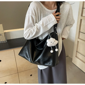Close-up of black tote bag with pleated texture and white cloud plush charm detail