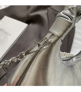 Close-up of metallic silver pleated handbag with pearl strap and chain detail