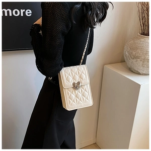 Detail of quilted crossbody phone bag featuring a silver heart-shaped twist lock