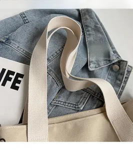 Detail of the durable beige canvas tote bag featuring a widened adjustable woven shoulder strap
