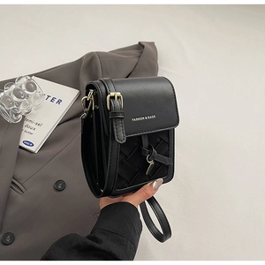 Detail of black leather crossbody bag featuring a woven texture and adjustable strap