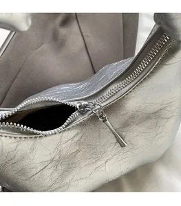 Detail of a smooth silver metal zipper and pleated texture on a soft leather cloud bag
