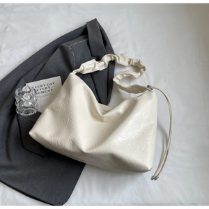 Close-up of white pleated tote bag with ruched shoulder strap and textured surface