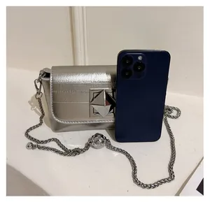 Compact silver metallic chain bag shown next to a smartphone for size comparison