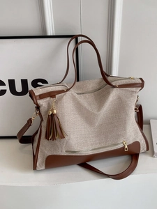 Large beige canvas tote bag with brown leather trim and tassel details, casual style