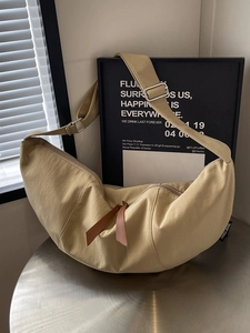 Minimalist beige nylon crescent crossbody bag with brown zipper and adjustable strap