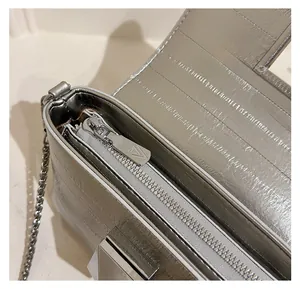 Detailed macro view of smooth silver zipper and embossed texture on the shoulder bag