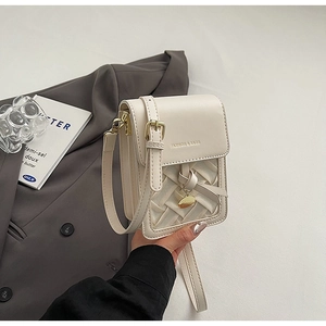Detailed close-up of cream leather crossbody bag with woven texture and gold pendant