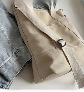 Detail of canvas tote bag showing adjustable shoulder strap and external pocket design