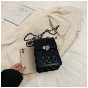 Detail of black quilted phone bag featuring a silver heart buckle and chain strap