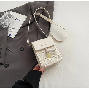 Close-up of cream square phone bag with woven texture and gold circular pendant detail