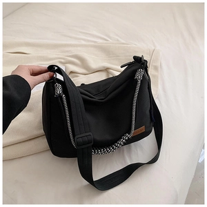 Détail du sac en toile noire avec poignée en corde tressée et écusson en cuir