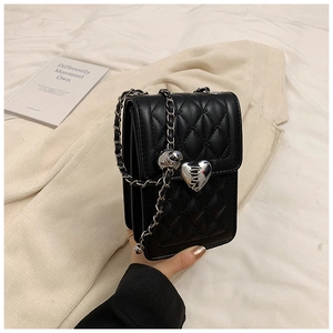 Close-up of black quilted leather phone bag with silver heart lock and chain strap