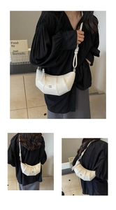 Détail d'un sac croissant blanc matelassé avec sangle nouée et finitions métalliques