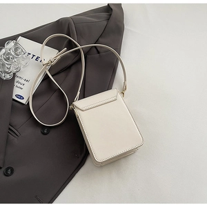 Close-up of cream square crossbody bag with rear pocket and adjustable strap detail