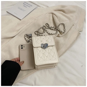 Close-up of white quilted phone bag featuring silver heart clasp and chain strap