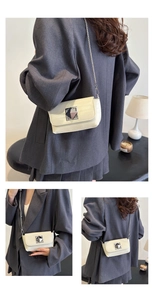Detail of a chic cream square bag with metallic buckle and silver chain strap