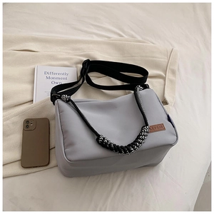 Détail d'un sac bandoulière en nylon gris avec sangle texturée et étiquette en cuir