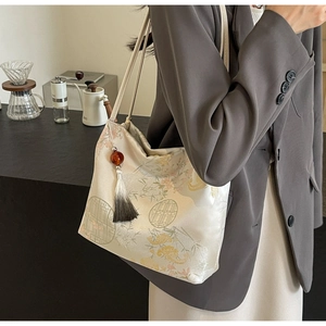 Detail of embroidered bamboo silk tote bag with decorative tassel and elegant pleats