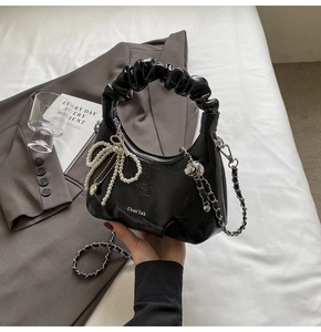 Détail du sac à main noir avec poignée plissée et nœud en perles élégant