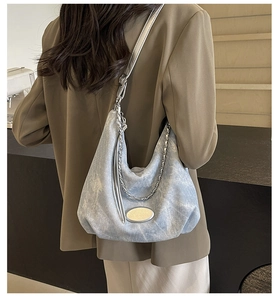 Detail view of light blue hobo bag with silver chain strap and oval metal plaque