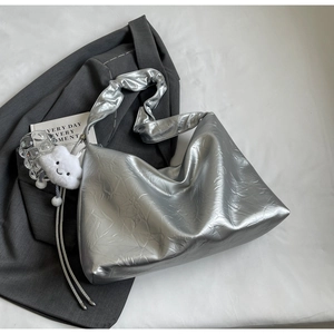 Detail of silver metallic tote bag with cloud charm and tassels on grey suit jacket