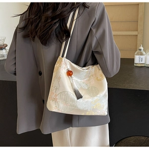 Detail of embroidered silk tote bag with traditional floral patterns and amber tassel