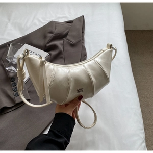 Détail du sac croissant crème avec rayures verticales et élégante frange en cuir sur le zip