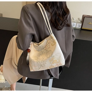 Detail of embroidered silk tote bag with bamboo patterns and tassel pendant on a model