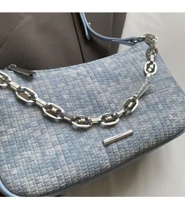 Détail du sac bandoulière tissé à carreaux bleus avec chaîne et lanière en cuir