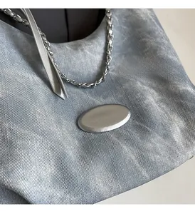 Detail of light blue metallic twill fabric with silver chain and oval metal buckle on bag