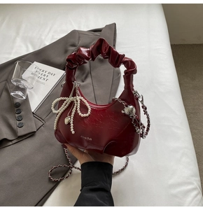 Détail du sac à main plissé rouge foncé avec breloque perle et bandoulière chaîne