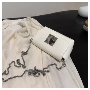 Close-up of white leather square bag featuring silver pyramid lock and chain strap