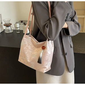 Detail of light pink silk tote bag featuring traditional Chinese embroidery and tassel