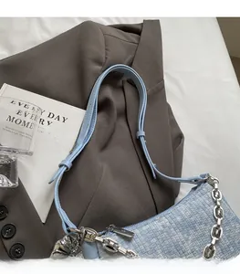 Gros plan du sac bandoulière en tweed bleu clair avec texture tissée et chaîne