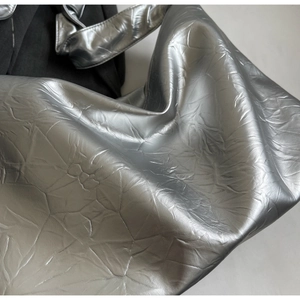 Detailed close-up of metallic silver tote bag featuring unique crushed crinkle texture