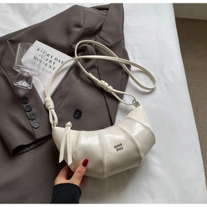 Détail d'un sac croissant chic crème avec logo métallique et bandoulière nouée