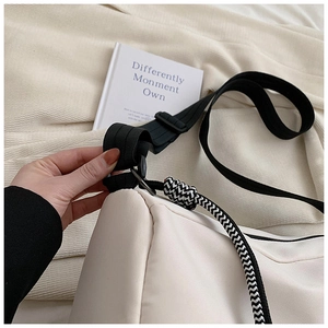 Gros plan d'un sac cabas en toile écru avec sangle noire et détail de nœud tissé