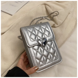 Detail of silver quilted cross body bag with metallic finish and heart-shaped buckle