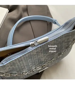 Gros plan du zip métallique et de la texture tissée bleue du sac à bandoulière femme