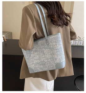 Détail d'un sac cabas tissé bleu clair avec bordures en cuir et logo métallique
