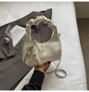 Détail du sac à main plissé blanc crème avec breloques perles et bandoulière
