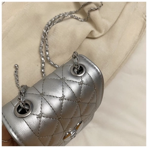 Detailed close-up of a silver quilted crossbody bag with heart-shaped metal lock